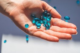A hand holding blue pills A hand holding blue pills