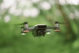 Drone flying against forest background Drone flying against forest background