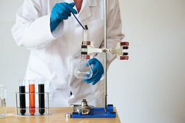 Scientist adding liquid to beakers with test tubes